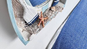 A room with a bunk bed, a nautical-themed wall, and a round mirror reflecting the room.