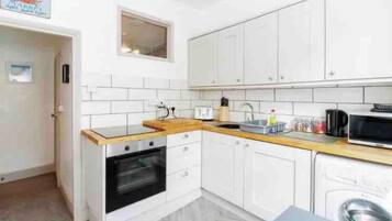 Una cocina compacta con armarios blancos, un microondas, una estufa y un lavabo.