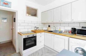 A compact kitchen with white cabinets, a microwave, a stove, and a sink.