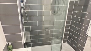 A modern bathroom with a glass shower enclosure, a white sink, and a toilet.