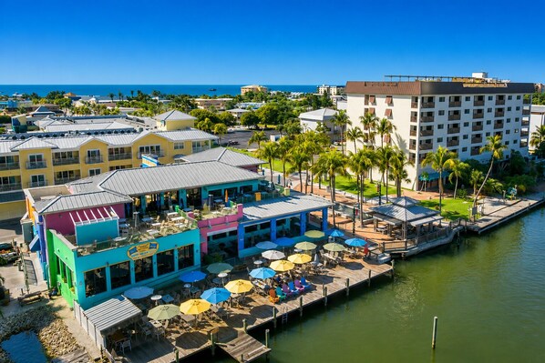 A waterfront hotel with outdoor seating, a dock, and a view of the ocean.
