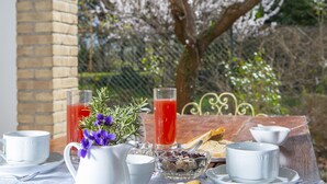 A breakfast setting with a table, two glasses of red beverage, a pitcher, a bowl of fruit, and a white teapot. - B&B with Pool and view of Assisi (Bastia Umbra/Assisi)