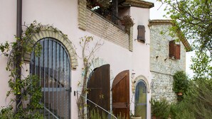 A traditional stone building with arched windows and doors, a stone staircase, and a garden with potted plants. - B&B with Pool and view of Assisi (Bastia Umbra/Assisi)