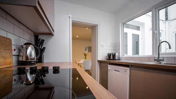 Una cocina moderna con estufa negra, encimera de madera y muebles de cocina blancos.