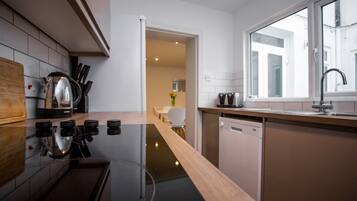 Una cocina moderna con estufa negra, encimera de madera y muebles de cocina blancos.