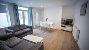 Una sala de estar moderna con un conjunto de sofá, una mesa de comedor con sillas, un televisor y un radiador.