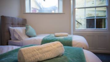 Un dormitorio con dos camas, cada una con cubrecama verde y almohadas blancas. Hay una ventana con vista a una montaña.