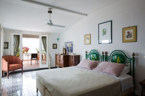 Una camera da letto con un letto, una sedia, una cassettiera e una ventola a soffitto.