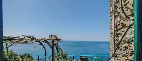 A stone building with a view of the sea, a pergola, and outdoor seating.