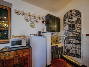 Een keuken met een magnetron, koelkast en decoratieve borden aan de muur.