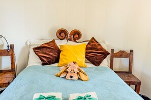A bed with a plush toy, pillows, and a bedspread.