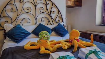 A bed with a metal headboard, blue pillows, and two octopus plush toys.
