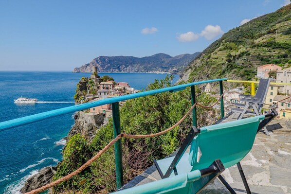 A coastal view with a chair, a rope barrier, and a boat on the water.
