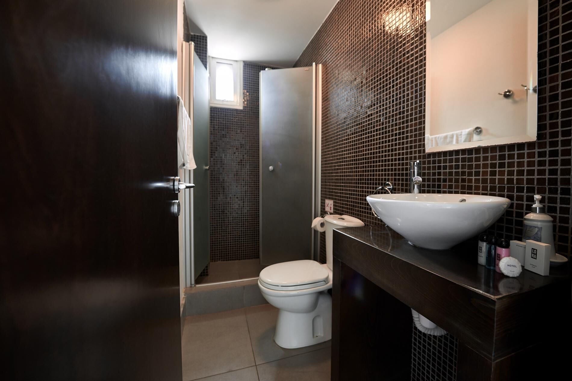 Un bagno moderno con un mobile bagno in legno scuro, un lavandino bianco e un water.