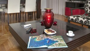 Una sala moderna con comedor, un jarrón rojo grande y un televisor.