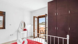 Ein Hotelzimmer mit Bett, Kleiderschrank, Schreibtisch und einem Balkon mit Blick.
