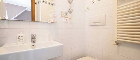 A bathroom with a white sink, a toilet, and a mirror.