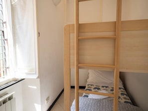 A bunk bed with a wooden frame and a mattress with a pattern. - Ventegà Sea View Apartment (Vernazza)