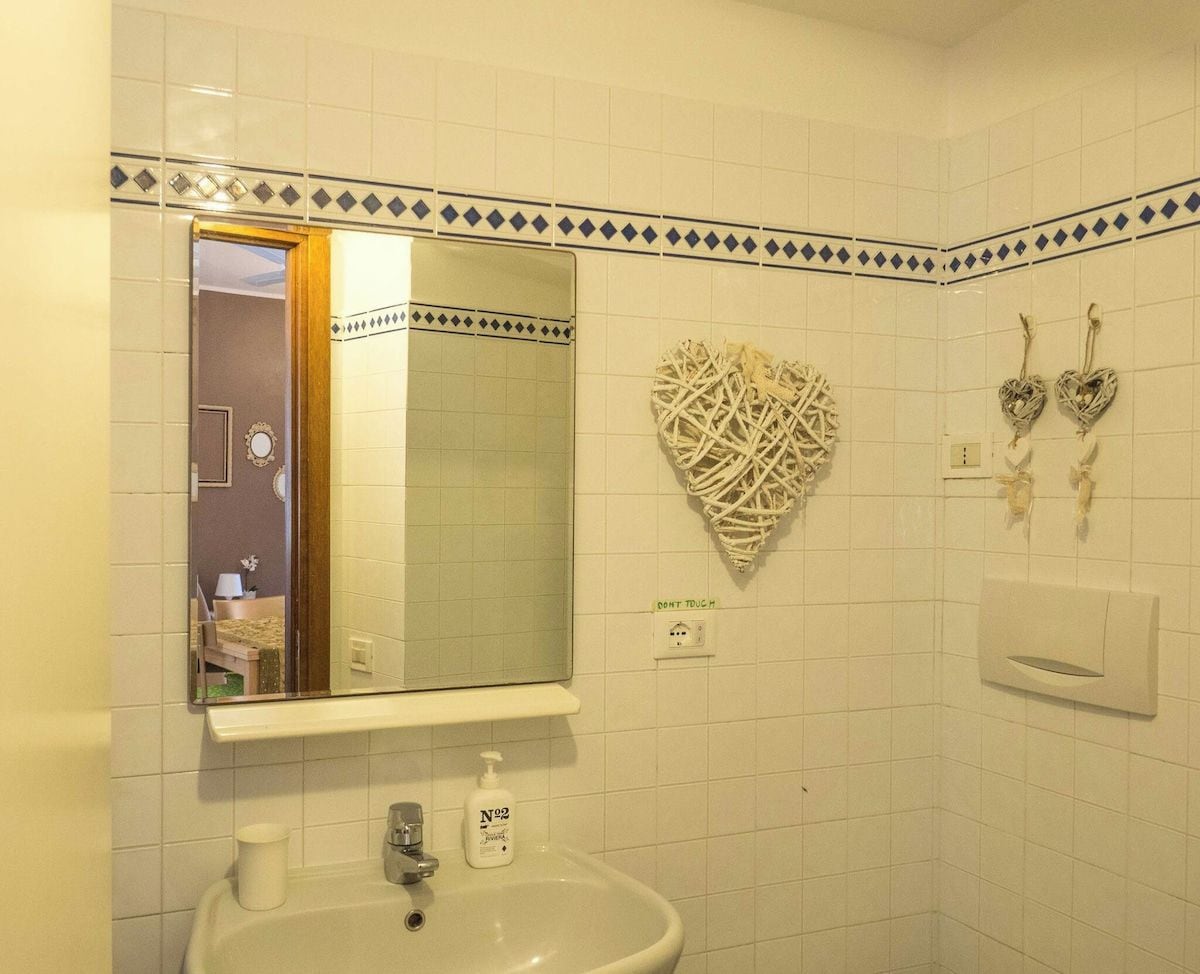Un baño con espejo, lavamanos y decoración de arte mural con forma de corazón.