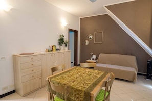 A small, well-lit room with a dining table, chairs, a sofa, a cabinet, and a staircase. - Ventegà Sea View Apartment (Vernazza)