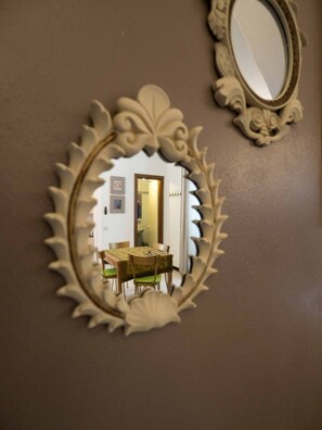 A mirror with an ornate frame reflecting a dining area with a table and chairs.