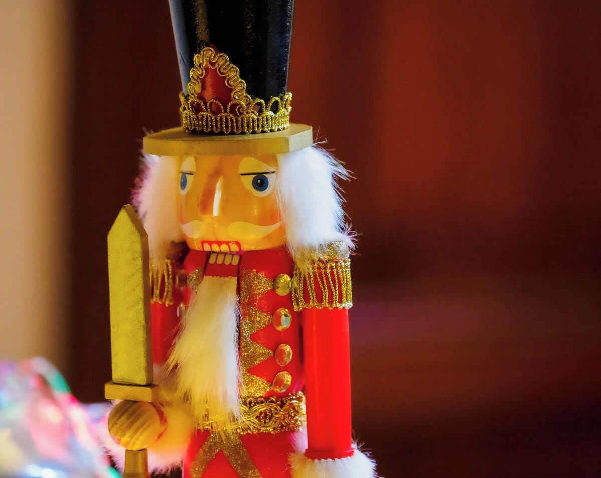 A nutcracker figurine with a sword, a black hat, and a red outfit with gold trim.