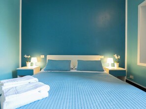 Ein Hotelzimmer mit einem großen Bett, zwei Nachttischen mit Lampen und einer blauen Wand.