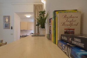 Una cocina con planta, una mesa de comedor y libros en la pared.
