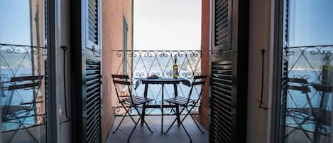 An outdoor balcony with a table and chairs, overlooking a body of water.