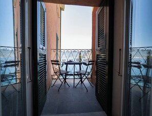 An outdoor balcony with a table and chairs, overlooking a body of water.