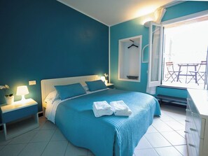 A bedroom with a bed, bedside tables, a window with a view, and a towel rack.