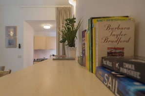A kitchen with a plant, a dining table, and books on the wall. - Ventegà Sea View Apartment (Vernazza)