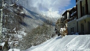 Una carretera nevada en la montaña con un edificio a la derecha.