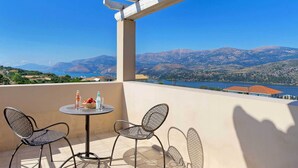 A balcony with two chairs, a table, and a view of mountains and a lake. - Villa Kalithea - Three Bedroom Villa, Sleeps 7 (Argostolion)