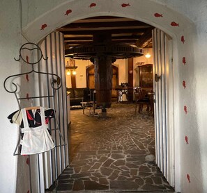 An arched doorway leading into a room with a stone floor, a wooden table, and a chair.