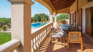 A covered patio with a pool, wooden furniture, and a view of greenery. - CAN MARINES - Villa with private pool in Calonge - Santanyí. Free WiFi. (Calonge)