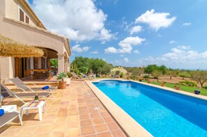 A swimming pool with lounge chairs and a patio area, surrounded by greenery and a clear sky. - CAN MARINES - Villa with private pool in Calonge - Santanyí. Free WiFi. (Calonge)