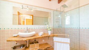 Une salle de bain avec un meuble-lavabo en bois, un lavabo blanc, une cabine de douche en verre et un miroir au-dessus du lavabo.