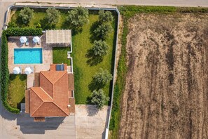 A residential property with a swimming pool, a covered patio, and a fenced garden area.