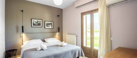 A hotel room with a bed, a desk, a radiator, and a window with curtains.