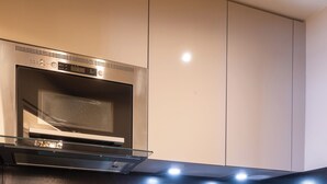 Una cocina moderna con microondas, cafetera y hervidor integrados en la encimera.