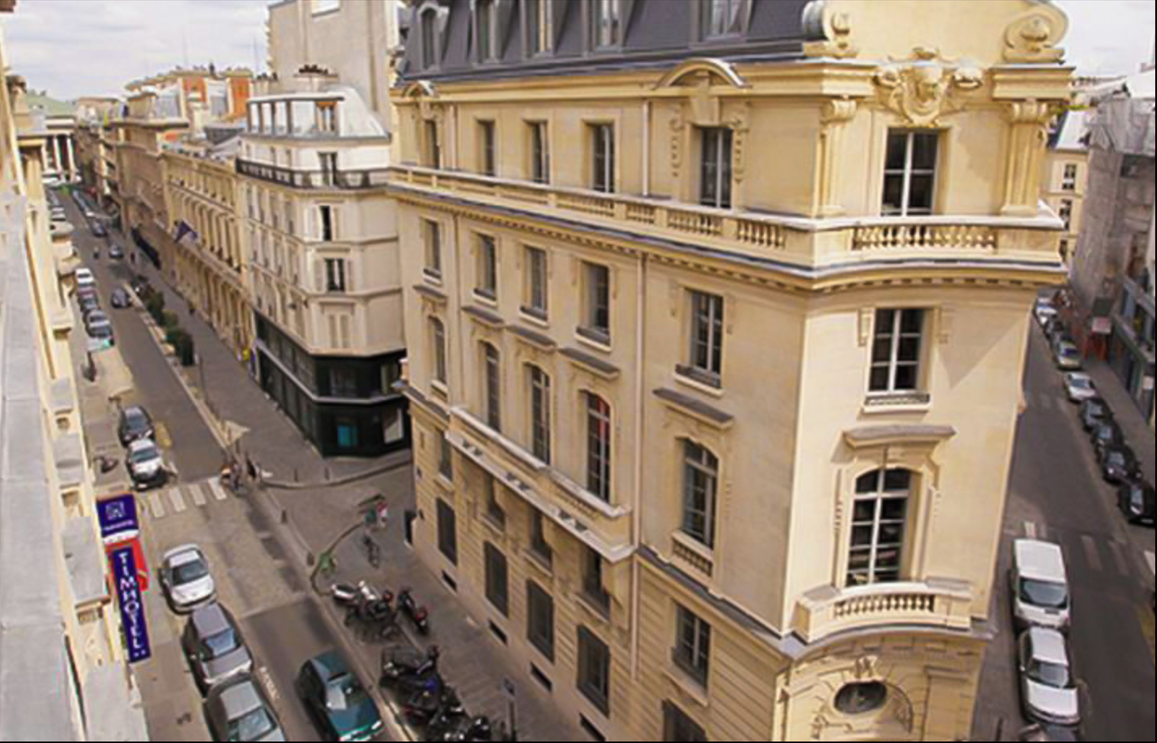 A multi-story building with a classical architectural style, featuring a central entrance with a balcony.