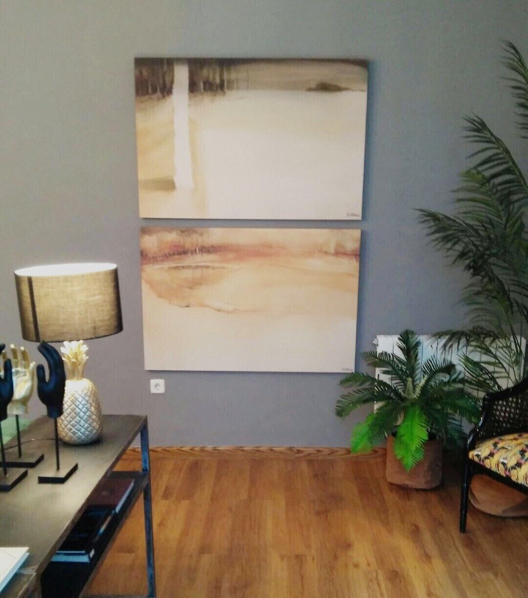 Ein Zimmer mit einem großen abstrakten Gemälde an der Wand, einer Lampe auf einem Tisch und einer Topfpflanze.
