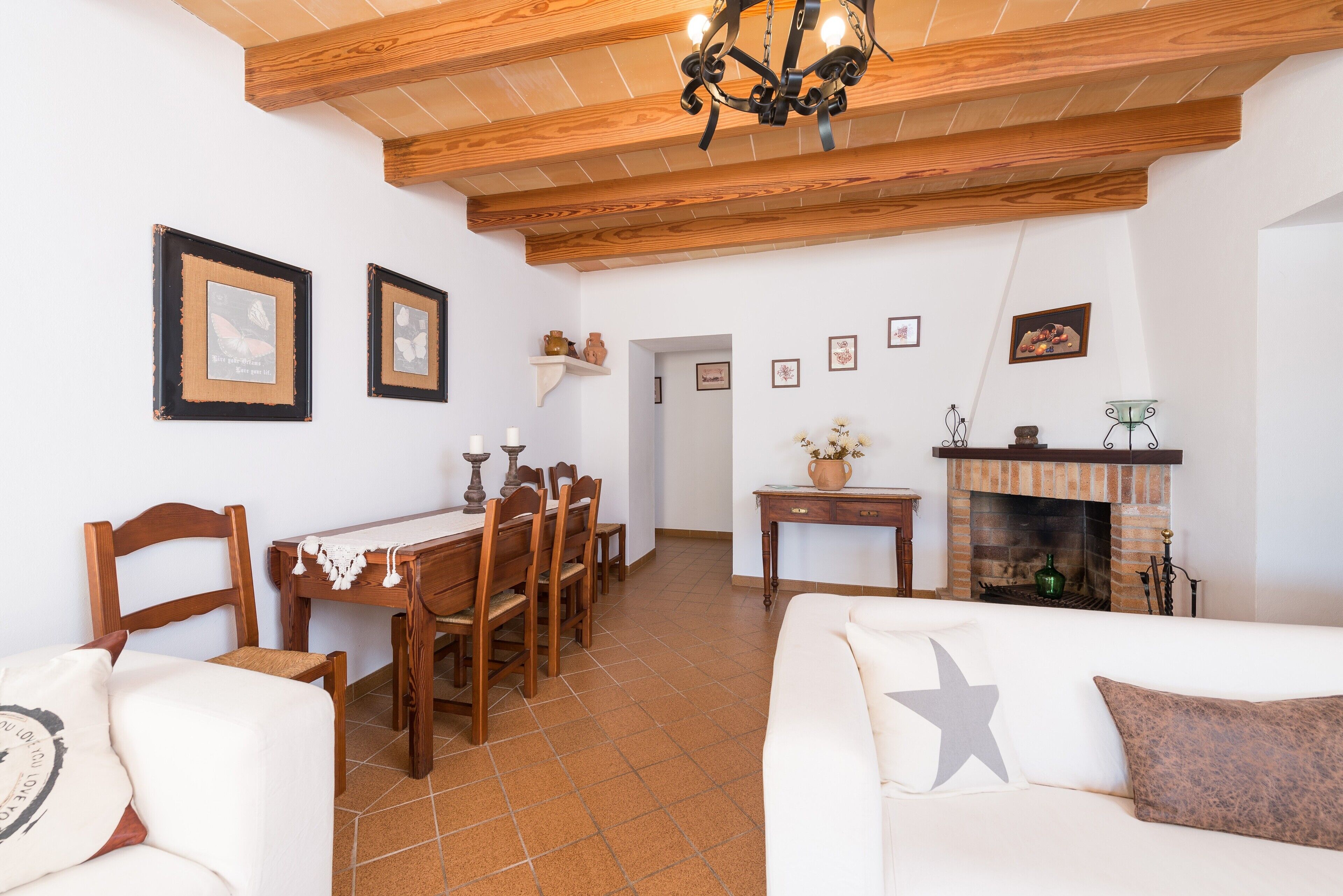 A dining area with wooden furniture, a fireplace, and framed pictures on the walls.