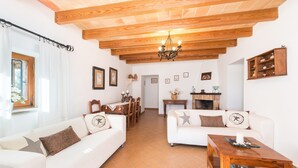 Una sala de estar con techo de madera, sofás blancos, una mesa de comedor y una chimenea.