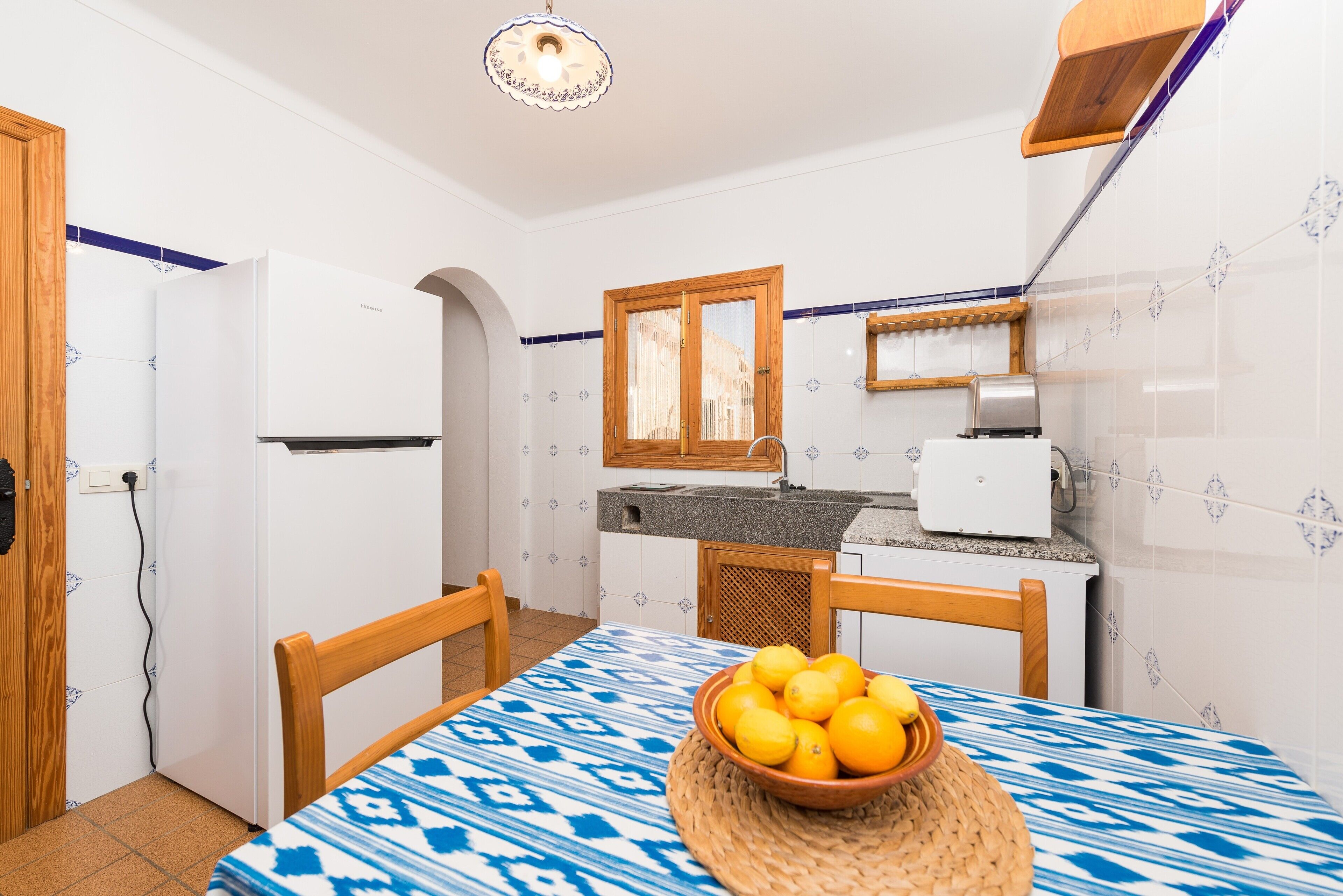 Une cuisine de taille réduite avec une table à manger, un bol de citrons et une chaise en bois.