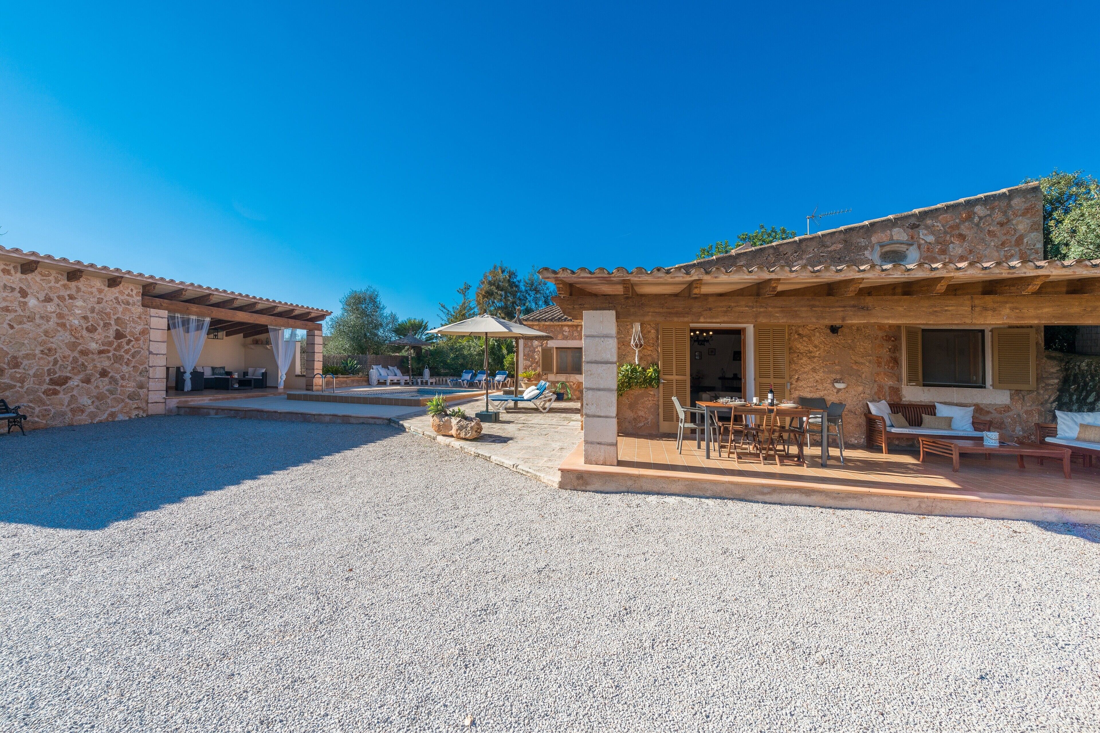 A stone building with outdoor seating and a pool area.