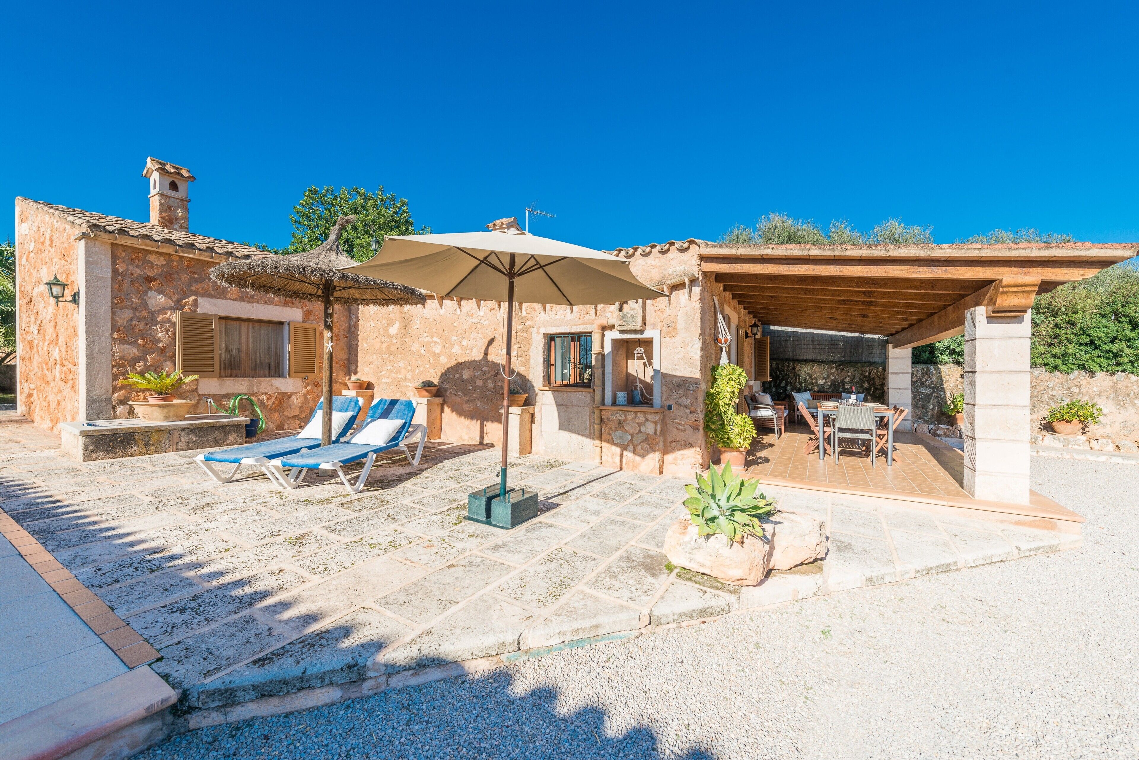 Un bâtiment en pierre doté d’un patio comprenant des chaises longues, une table et un barbecue.