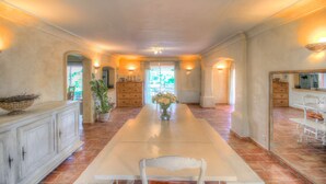 A spacious dining area with a long table, chairs, and a vase of flowers. -  The Vignaux bastide (Grimaud)
