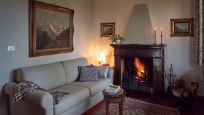 A living room with a sofa, a fireplace, a rug, and a painting on the wall. - Le Balze Charming Apartment in villa, private garden, 10 min from Perugia Centre (Perugia)